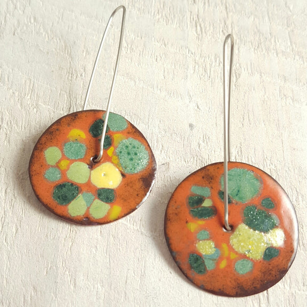 Orange enameled copper earrings with green accents.