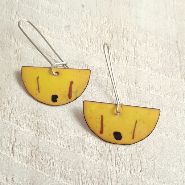 Yellow enameled copper earring with black and red accents.