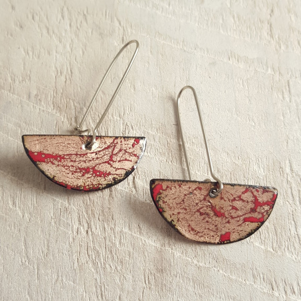Transparent enameled copper earrings with red swirl accents.
