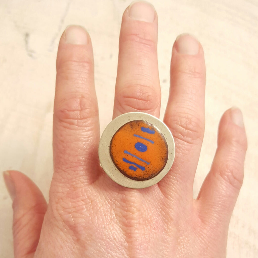 Orange enameled copper ring with blue accents.